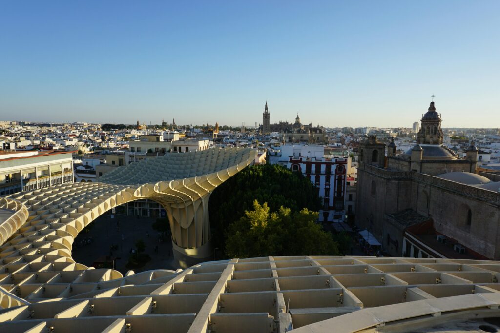 Panoramic view of Metropol Parasol and Seville skyline at sunset with historical landmarks.
